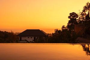 - un coucher de soleil sur une maison et une piscine dans l'établissement Luxury Seaview Villa, Infinity Pool, Sunset, à Karon Beach
