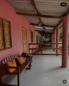 a porch with two benches on a pink wall at Recanto Monte das Oliveiras Hotel e Pousada in Tupim