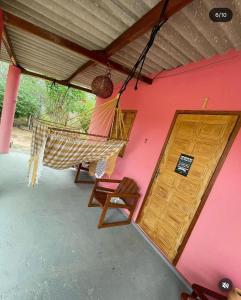 a porch with a hammock and a pink wall at Recanto Monte das Oliveiras Hotel e Pousada in Tupim