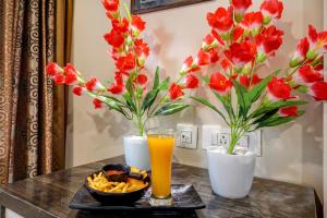 a table with red flowers and a glass of orange juice at Hotel Marina FREE Airport Drop in New Delhi