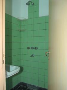een groene betegelde badkamer met een wastafel en een douche bij LalomitaGesell in Villa Gesell
