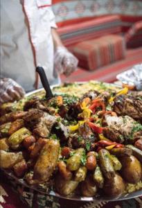 a plate of food with meat and vegetables on a table at mountains wadi rum in Disah +22 photos
