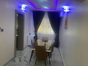 Un comedor con una mesa e iluminación violeta. en NewClime Apartment, en Abuja