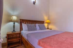 a bedroom with a bed and two lamps on tables at Riverside Suites Buwate in Kampala