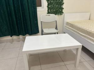 a white table and a chair in a room at AG DORMS and BUNKS in Doha