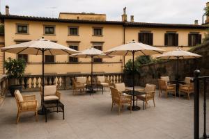 a patio with tables and chairs and umbrellas at Incanto Relais & Charme - dBe Hotels in Florence