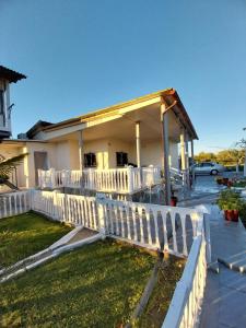 a white fence in front of a house at Villa Artzie. Έξοχικο με τεράστιο εξωτερικό χώρο. in Nea Kalikratia