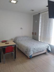 a bedroom with a bed and a table and a desk at Departamento El Marques in Rada Tilly