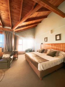 a bedroom with a large bed and a chair at Las Bayas Home Suites in Esquel