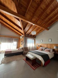 a bedroom with two beds and a wooden ceiling at Las Bayas Home Suites in Esquel