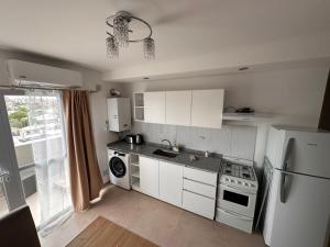 a kitchen with white cabinets and a white refrigerator at urbano in Neuquén +5 photos