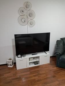 TV de pantalla plana en un centro de entretenimiento blanco en Casinha da Palmeira, en Nazaré