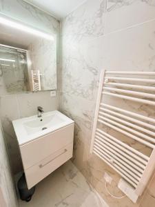 a white bathroom with a sink and a mirror at Le Cocon Mévennais in Saint-Méen-le-Grand