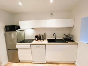 a kitchen with white cabinets and a sink and a refrigerator at Le Cocon Mévennais in Saint-Méen-le-Grand +12 photos
