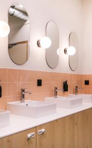 a bathroom with three sinks and two mirrors at Mustard Hostel in Dijon