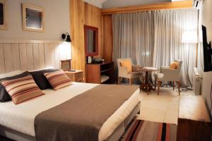 a hotel room with a bed and a table and chairs at Las Bayas Home Suites in Esquel +15 photos