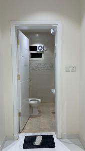 a bathroom with a toilet and a door open at شقق واڤا in Tabuk