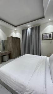a bedroom with a large white bed and a window at شقق واڤا in Tabuk