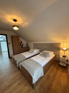 zwei Betten in einem großen Zimmer mit Holzboden in der Unterkunft Domy na Roztoczu Aleja Lipowa B,G,J,K Sauna Jacuzzi Kajaki in Zwierzyniec + 79 Fotos