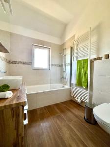 a bathroom with a tub and a toilet and a sink at Ferienwohnung am Kräutergarten im Hunsrück 