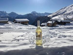 a bottle of wine and two glasses in the snow at Chalet Abendruh Belalp in Naters