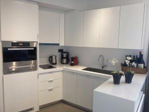 a white kitchen with white cabinets and a sink at Arion Hotel in Kórinthos