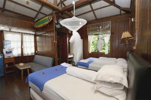 a bedroom with two beds and a couch and a chandelier at Arya's Surf Camp Cimaja in Sukabumi