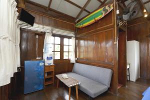 a living room with a couch and a surfboard on the wall at Arya's Surf Camp Cimaja in Sukabumi