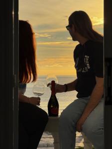 una mujer sosteniendo una botella y una copa de vino en Thalassa apartments, en Marathias