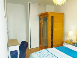 a bedroom with a bed and a wooden cabinet at Apt au calme, 2-3 chambres, Sauna, 2 parkings, bus sur place in Montévrain