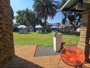 a patio with an orange fan and a yard with umbrellas at Zhantique Guest House 2- Unit 11 in Boksburg