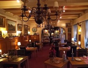 ein Restaurant mit Tischen und Stühlen und einem Kronleuchter in der Unterkunft Hotel Le Chalet in La-Roche-en-Ardenne