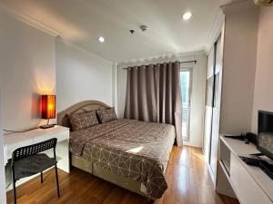 ein Schlafzimmer mit einem Bett, einem Schreibtisch und einem Fernseher in der Unterkunft Dina Cozy House in Jakarta