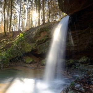 a waterfall in the woods next to a river at Ferienwohnung Martha und Nikla in Philippsheim