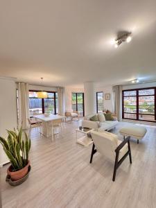 Arriaga Marina Club Apartament في فونشال: غرفة معيشة كبيرة مع أثاث أبيض ونوافذ