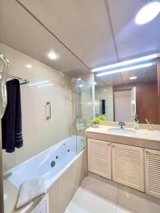 Arriaga Marina Club Apartament في فونشال: حمام مع حوض استحمام ومغسلة ودش