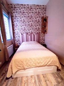 a bed in a room with a brick wall at A l'abri des vagues in Cayeux-sur-Mer