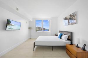ein weißes Schlafzimmer mit einem Bett und einem Fenster in der Unterkunft Beach Escape with Balcony & Resort Amenities in Hallandale Beach + 25 Fotos