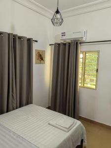une chambre avec un lit et une fenêtre avec des rideaux dans l'établissement Magnifique Appartement 2 chambres Salon, à Cotonou