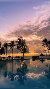 a swimming pool with palm trees and a sunset at Nautical Nest Beachfront Apartments in Malindi +16 photos