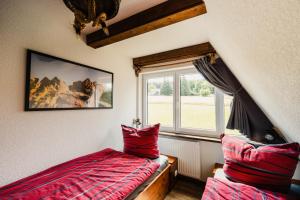 a bedroom with a red bed and a window at Ferienhaus Lärchenblick in Kurort Altenberg