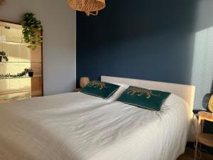 ein Schlafzimmer mit einem weißen Bett mit zwei grünen Kissen in der Unterkunft Kaksio järvinäkymällä ja saunalla Lahden Satamasta in Lahti