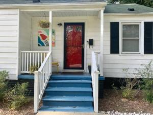 a red door on a white house with blue stairs at Downtown - 2 bed, 1 bath - KC in Raleigh