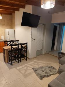 ein Wohnzimmer mit Tisch und Stühlen und einem Fernseher in der Unterkunft Departamentos Negretti in Junín