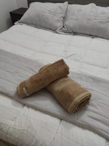 ein braunes Handtuch auf einem weißen Bett in der Unterkunft Departamentos Negretti in Junín