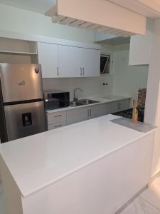 a kitchen with white cabinets and a stainless steel refrigerator at Residencial cayena del este Santo Domingo este in La Grúa