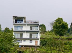 科代卡纳尔Kurinji Kudil Homestay - Kodaikanal的一座公寓楼,位于一座树木繁茂的山丘上