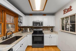a kitchen with white cabinets and a black stove top oven at The Mountain Forager Cabin, Bryson City NC in Bryson City