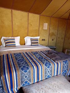 a bedroom with two beds in a tent at Tasnim Désert Camp & Activités in Merzouga
