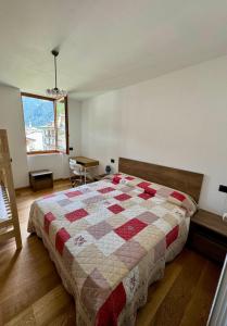 a bedroom with a bed with a quilt on it at Appartamento Conca Epolo in Schilpario